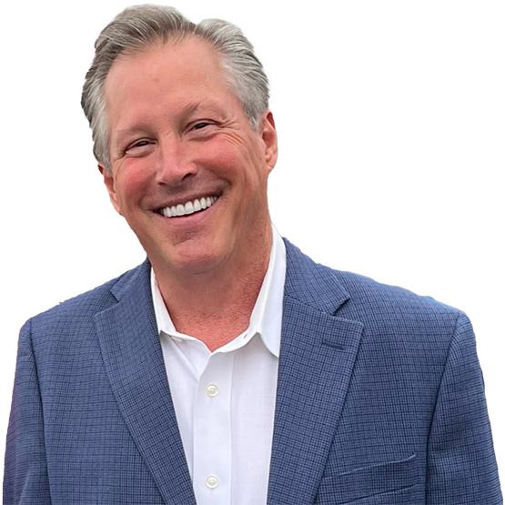 Reid Stinnett smiling in a suit jacket against a transparent background.